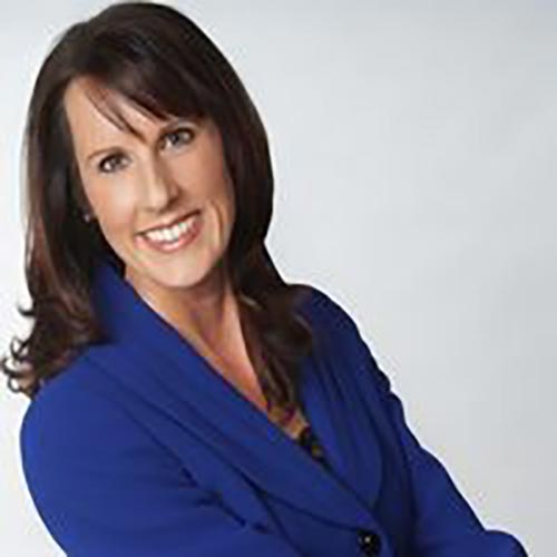 A woman in blue jacket smiling for the camera.