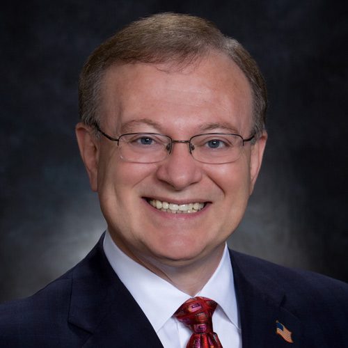 A man in suit and tie smiling for the camera.