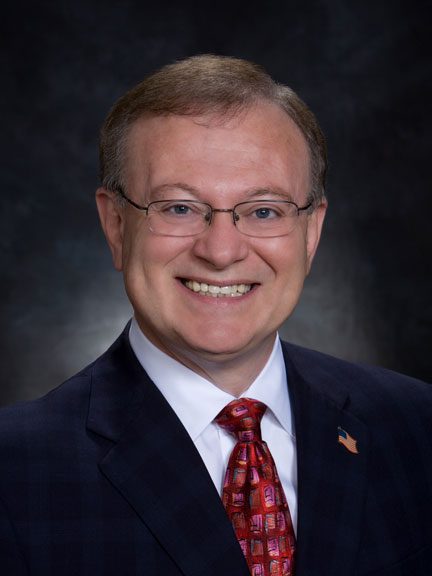 A man in suit and tie smiling for the camera.