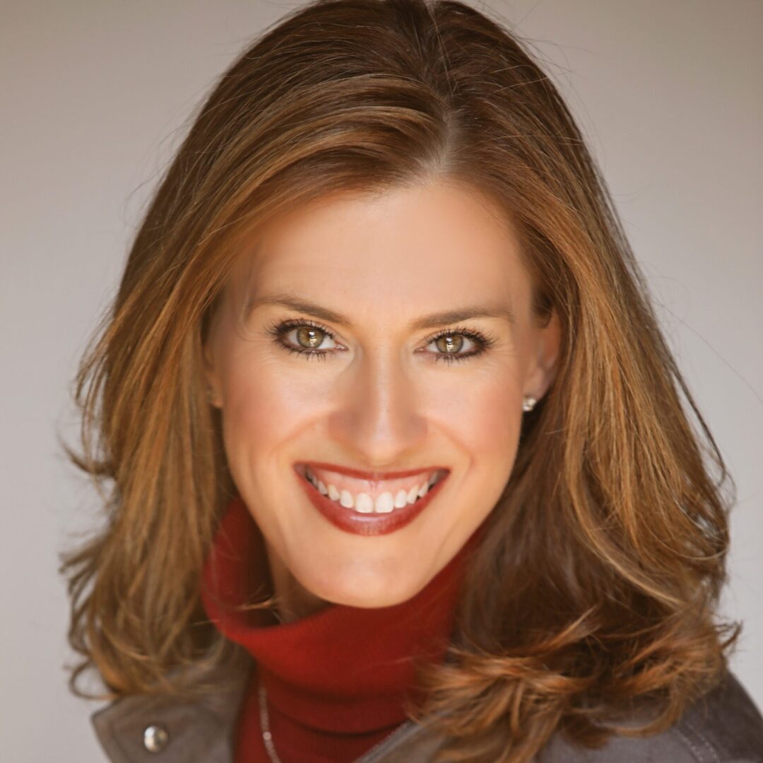 A woman with long hair and red lipstick smiles.