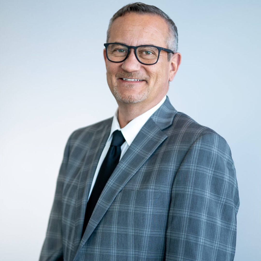 A man in a suit and tie standing next to a wall.