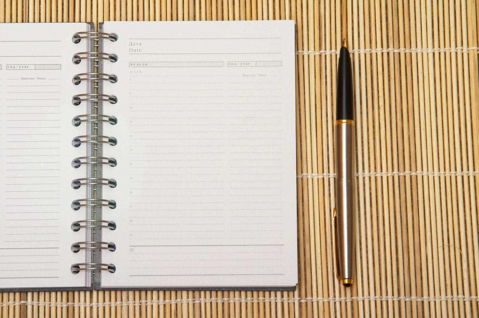 A pen and notebook on a bamboo mat.